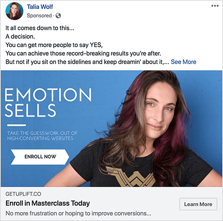 Toto je snímka obrazovky z Facebookovej reklamy na masterclass od Talia Wolfovej. V reklamnom texte je každá veta v samostatnom riadku. Píše sa tam „Všetko závisí od toho... Rozhodnutie. Môžete presvedčiť viac ľudí, aby povedali ÁNO. Môžete dosiahnuť tie rekordné výsledky, ktoré sledujete. Ale nie, ak sedíte bokom a stále o tom snívate... „Za týmto textom sa nachádza odkaz Zobraziť ďalšie. Obrázok reklamy má modré pozadie s bielym textom a obrázok Tálie od hrude nahor. Je to biela žena s hnedými a fialovými vlasmi, ktoré jej padajú pod plecia. Oblečené má čierne tričko so zlatým logom Wonder Woman. Text naľavo od jej fotografie hovorí „Emotion Sells“ a „Take the guesswork from high-conversing websites“. Pod týmto textom je biela šípka s čiernym textom, ktorá hovorí „Zaregistrovať sa teraz“. Pod obrázkom je nasledujúci nadpis a text: „Getuplift.co“ a „Zaregistrujte sa na Masterclass Today“ a „Už žiadne frustrácie alebo nádeje na zlepšenie konverzií“. Vpravo dole sa zobrazí tlačidlo Ďalšie informácie.